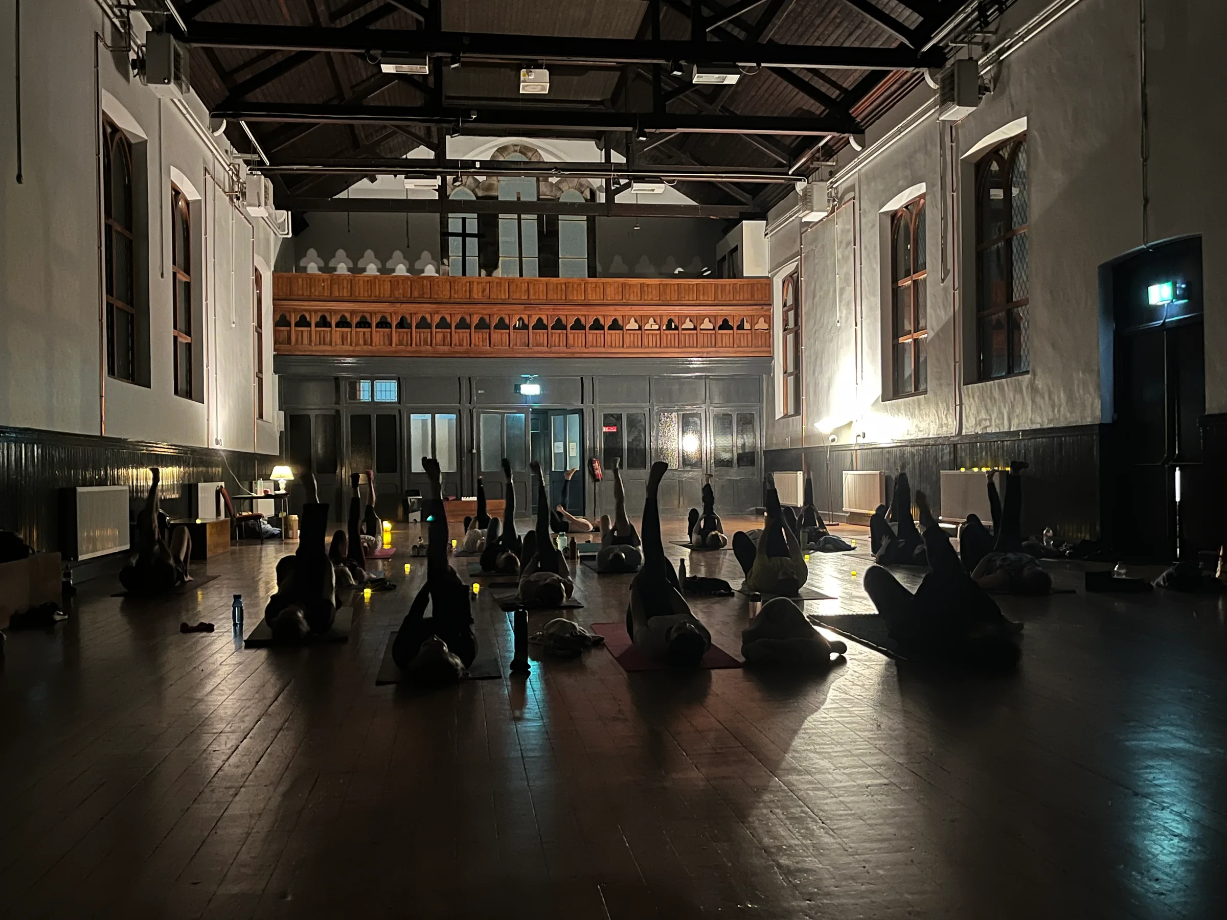 Evening yoga class in St. Anthony's Hall with soft candlelight creating a peaceful, meditative atmosphere